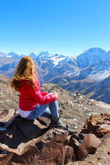 The girl with bright red hair overlooking the mountains with glaciers