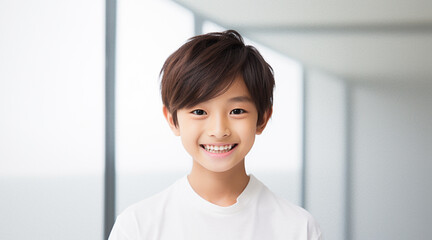 白く明るい窓を背景に、白い服を着て一人で写真に写る日本人の少年 - obrazy, fototapety, plakaty