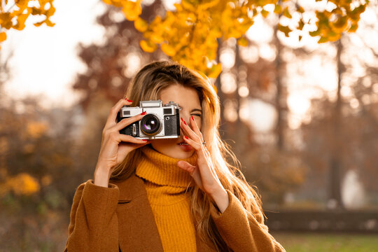 Closeup shot of young beautiful woman taking picture with analog camera 