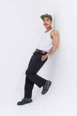 Isolated cutout studio shot Asian vintage classy mustache with neck arms hands tattoos male fashion model in casual fashionable sleeveless shirt cap boots posing standing on white background.