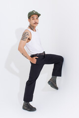 Isolated cutout studio shot Asian vintage classy mustache with neck arms hands tattoos male fashion model in casual fashionable sleeveless shirt cap boots posing standing on white background.