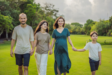 A loving family enjoying a leisurely walk in the park - a radiant pregnant woman after 40, embraced by her husband, and accompanied by their adult teenage children, savoring precious moments together