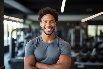 Fototapeta premium Smiling portrait of a happy young male african american fitness instructor in an indoor gym