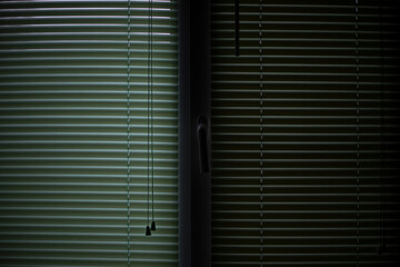 Green blinds on window. Dim light in room. Blinds background.