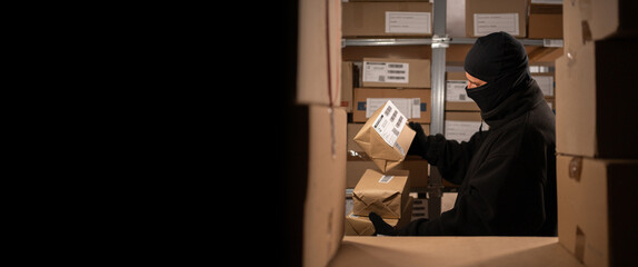 A thief stealing boxes in a warehouse at night in the dark. Warehouse and store security concept