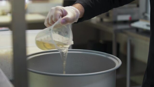 A worker is pouring the cooking oil inside of the huge container. Pouring the oil into the pot for cooking fast food. Chef is slowly pouring the oil into the cooking pot. Fast Food Restaurant.