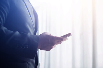 Businessman using smartphone, success after monthly meeting, corporate window background, success concept