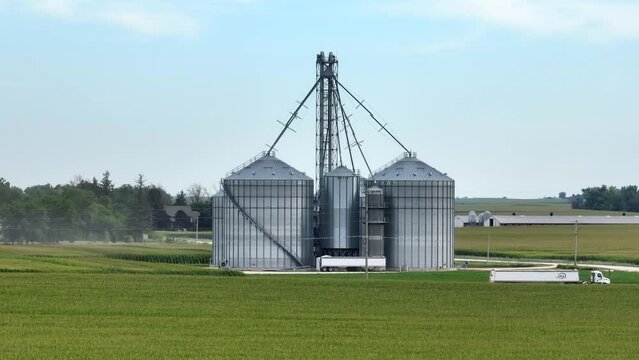 Large grain elevator in midwest USA. Aerial shot of semi truck hauling corn and grains. Long zoom lens above field.