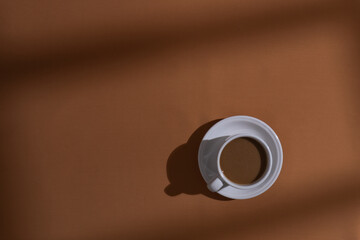 Coffee and cookies on brown background with window shadow, aesthetic morning background concept
