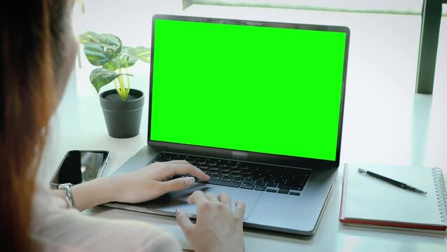 Hands of young woman over laptop keypad during working, blank green screen 4K template footage