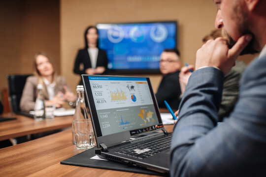 Business meeting in the conference room. A businesswoman is talking to her colleagues while an animated chart data is displayed on the computer screen. - Powered by Adobe
