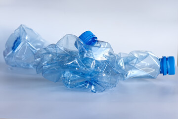 Two crushed blue plastic bottles, recyclable plastic bottle, reduce size, recycling.