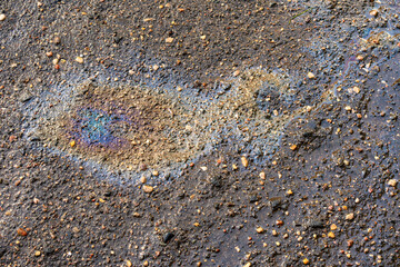 Leakage of oil or gasoline from under the car on the asphalt in the parking lot.