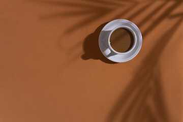 Coffee and cookies on brown background with plant shadow, aesthetic morning background concept
