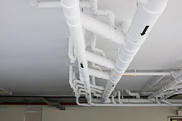 The white pipe system is installed on the ceiling of a building or factory.