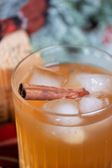 Whiskey cocktail in a glass with ice and a cinnamon stick with a juniper branch in the background...