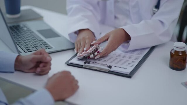 Close up of doctor's hands is explaining and advising about using pills medicine and treatment to patient.