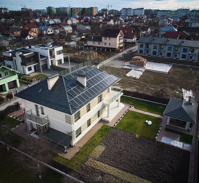 Aerial view of residential autonomous house with photovoltaic solar panels. Houses, homes, streets and buildings with solar electric system in new suburban district.