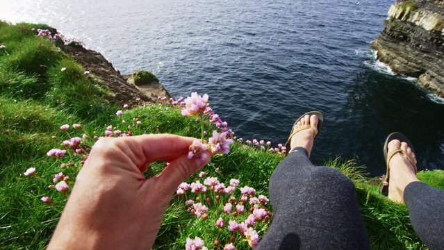 Point of view picking flower on cliff edge and looking out at sea. Dun Briste Sea Stack Ireland.