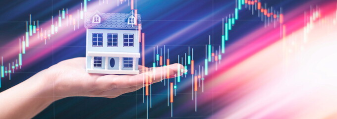 The concept of buying and selling real estate. A man with a model of a house on the background of the forex chart.