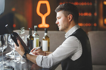 Sommelier looks at bottle of expensive wine in bar.