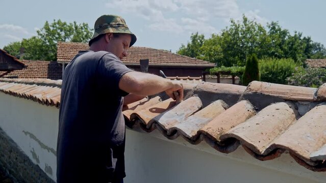 Man on work platform brush cleans terracotta tiled wall of cement dust