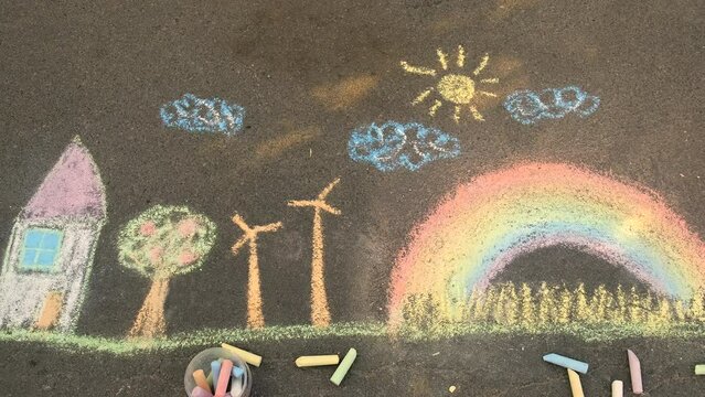 A child draws a rainbow on the pavement. Selective focus.