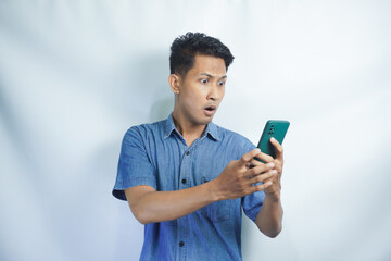 Fototapeta premium Attractive young Asian man talking on his phone, getting bad news, shocked mad angry gesture