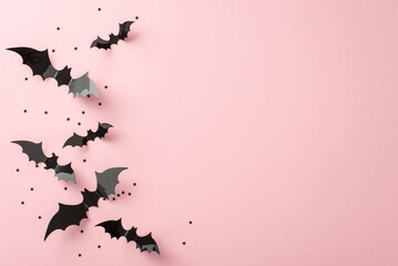 Chic Halloween trick-or-treat idea. Top view of thematic elements: bat silhouettes, and star shaped confetti on soft pink background. Empty space for greetings or promos