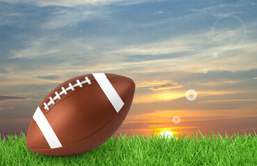 American football ball on a grass against the sunset