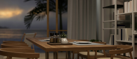 A wooden dining table in a cozy dining room with a beautiful beach sunset view through the window.