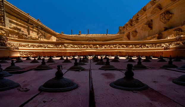 Detailed view from below of the ornaments on the red wooden main door with wrought iron motifs and the cornice with bas-reliefs of animals, beasts, chimeras and gargoyles of the Cathedral of Salamanca