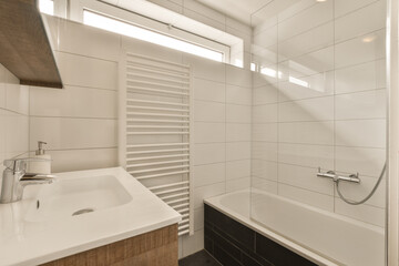 Fototapeta na wymiar a bathroom with white tiles on the walls and wood trim around the tub, sink, and faucet