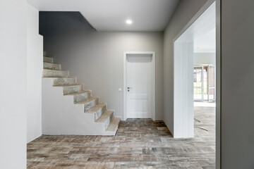 A room in a private house immediately after laying the floor, white unfinished walls and ceiling