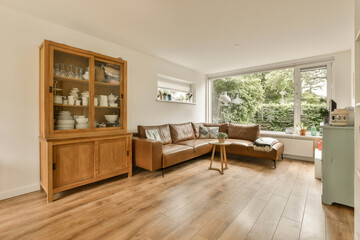 a living room with wood flooring and large windows looking out onto the garden outside from the open kitchen area