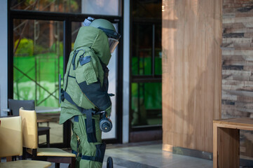 Bomb disposal officers wearing protective gear Investigating a suspected bomb in the airport building. with remote robotic arm