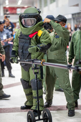 Bomb disposal officers wearing protective gear Investigating a suspected bomb in the airport building. with remote robotic arm