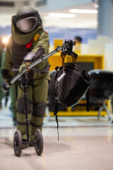 Bomb disposal officers wearing protective gear Investigating a suspected bomb in the airport building. with remote robotic arm