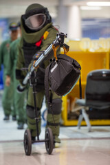 Bomb disposal officers wearing protective gear Investigating a suspected bomb in the airport building. with remote robotic arm