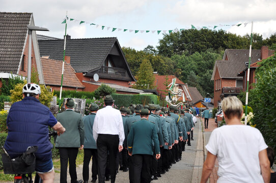 Sch&uuml;tzenfest ist: Sch&uuml;tzen in Uniform marschieren durch die Siedlung zum Sch&uuml;tzenplatz, von hinten fotografiert.
