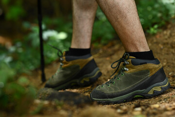 Male legs with hiker boots walking along the forest path. Traveling and adventure concept