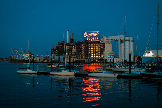 Domino Sugars Factory vintage neon sign and the harbor at night in Baltimore, Maryland