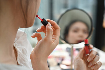 Cropped image of young woman applying lipstick in front of a mirror and recording make up tutorial at home
