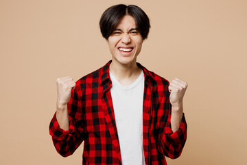 Young man of Asian ethnicity he wear red checkered shirt casual clothes doing winner gesture...