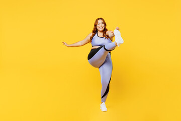 Fototapeta na wymiar Full body fun young chubby plus size big fat fit woman wear blue top warm up training raise up leg do stretch hand exercise isolated on plain yellow background studio home gym. Workout sport concept.