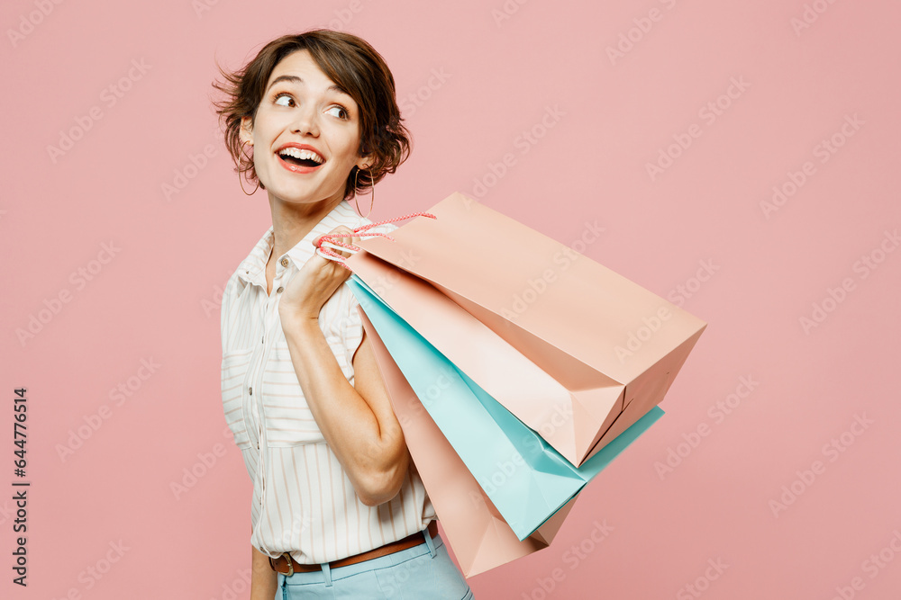 Sticker Side view young smiling woman wears casual clothes hold shopping paper package bags look aside on area isolated on plain light pastel pink color background studio. Black Friday sale buy day concept.