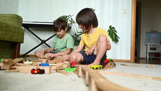 Brothers playing with wooden toys sitting on floor