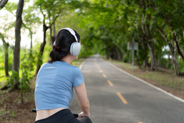 Young woman listening to music with headphones while biking in the park