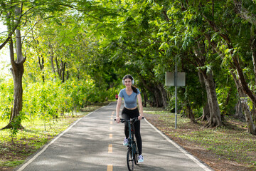 Young woman listening to music with headphones while biking in the park