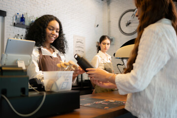 Young woman barista serves customers who bring their own cups in a coffee shop.